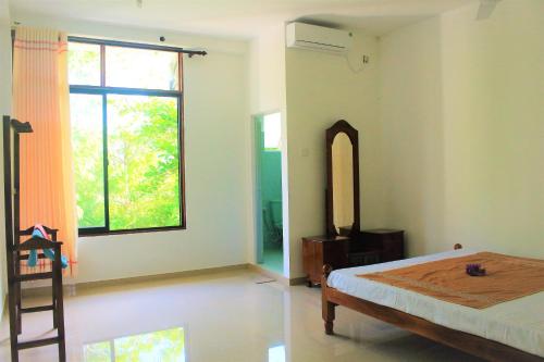 a bedroom with a bed and a large window at Samanala Resort in Matara