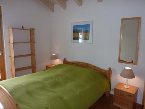 a bedroom with a green bed and two lamps at Apartments Scierie in Vercorin