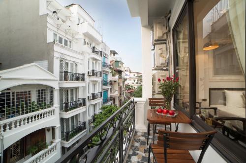 einen Balkon mit einem Tisch, Stühlen und Gebäuden in der Unterkunft Galliot Central Hotel in Hanoi