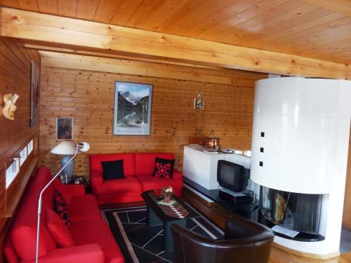 a living room with a red couch and a tv at Chalet Mon Sabot in Vercorin