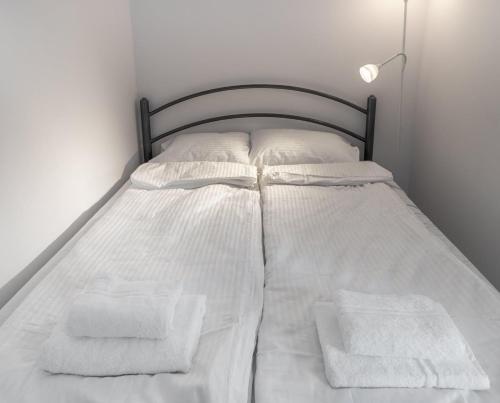 un letto con lenzuola e asciugamani bianchi di Apartament Szarych Szeregów 46A/1 a Katowice