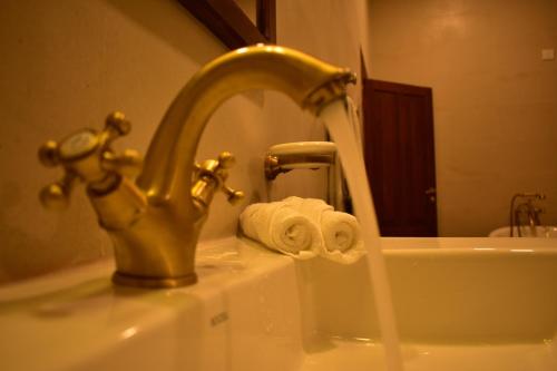 a bathroom sink with a faucet and a roll of toilet paper at Hill Cottage in Nuwara Eliya