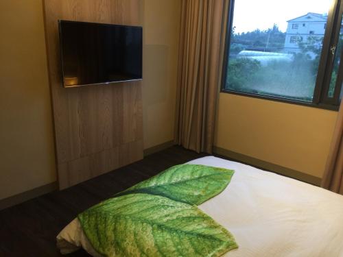 a bedroom with a bed with a leaf pillow and a window at San Yuan Guest House in Jinning
