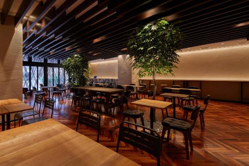 a restaurant with wooden tables and chairs and plants at Centurion Hotel Classic Nara Station in Nara