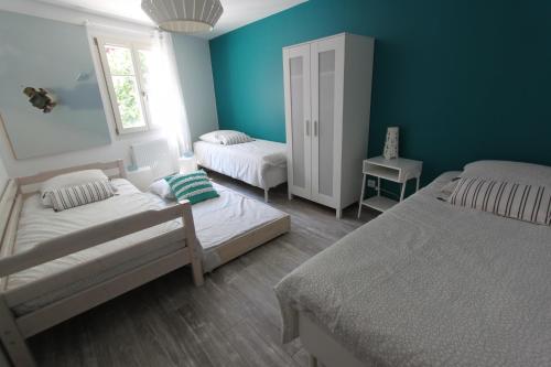 sypialnia z 2 łóżkami i niebieską ścianą w obiekcie Subtil insolite w mieście Colmar