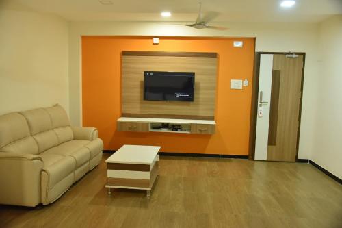 a living room with a couch and a flat screen tv at Santhoshpuri in Coimbatore