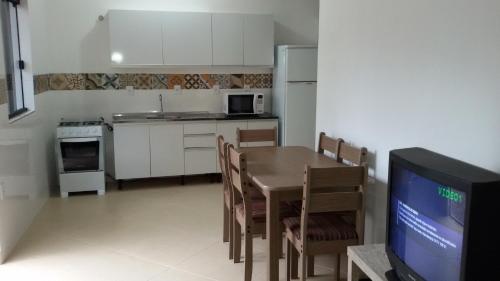 a kitchen with a table and a tv in a room at Casa Barra de Ibiraquera. Há menos de 5minutos caminhando da lagoa e do mar. in Barra de Ibiraquera