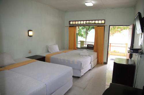 A bed or beds in a room at Pandu Lakeside Hotel Parapat