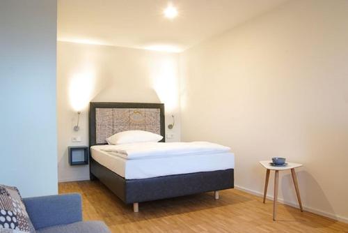 a small bedroom with a bed and a chair at SEEGER Living Premium Downtown in Karlsruhe