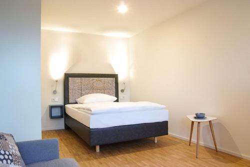 um pequeno quarto com uma cama e uma cadeira em SEEGER Living Premium Downtown em Karlsruhe