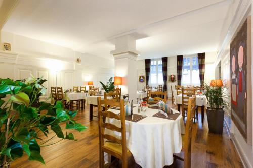 a dining room with tables and chairs and plants at Hôtel Restaurant La Cigogne in Munster