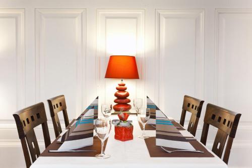 a dining room table with a lamp and chairs at Hôtel Restaurant La Cigogne in Munster