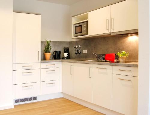 eine Küche mit weißen Schränken und einer Mikrowelle in der Unterkunft SEEGER Living Premium West in Karlsruhe