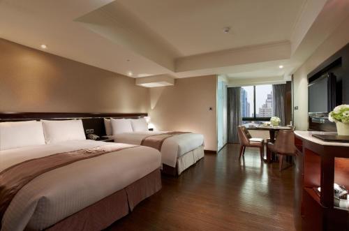 a hotel room with two beds and a table at Taichung Charming City Hotel in Taichung
