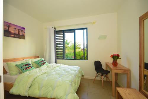 a bedroom with a bed and a window and a chair at Azuri Resort -Sea View & Golf Luxury Apartment in Roches Noires