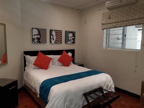 1 dormitorio con 1 cama grande con almohadas rojas y azules en Glendower View Guest House, en Johannesburgo