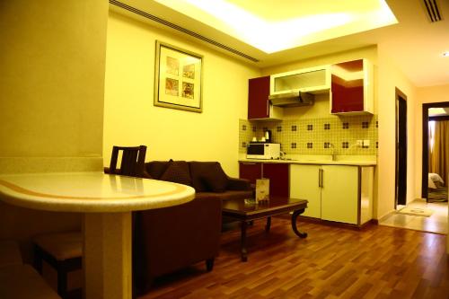 أجنحة سنام الفندقية في الرياض: غرفة معيشة مع أريكة وطاولة ومطبخ