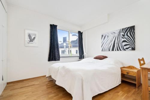 a white bedroom with a bed and a zebra picture on the wall at Apartment Bergen Central in Bergen
