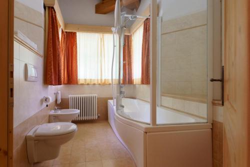 a bathroom with a tub and a toilet and a sink at Agritur Cornasest in Breguzzo