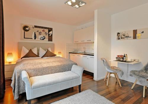 a bedroom with a bed and a chair and a kitchen at Design Apartment nähe Düsseldorf in Krefeld