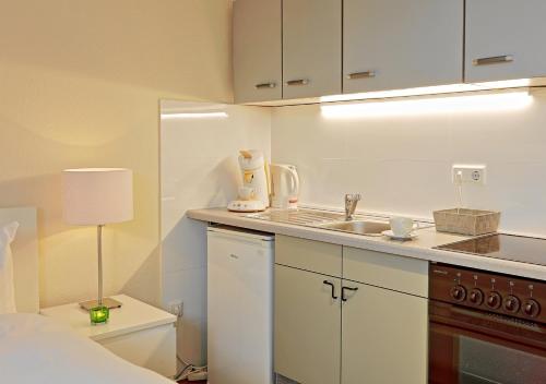 a white kitchen with a sink and a lamp at Design Apartment nähe Düsseldorf in Krefeld