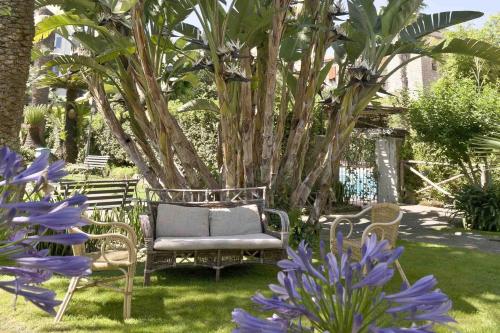 a garden with two chairs and purple flowers at Hotel Eden in Sorrento
