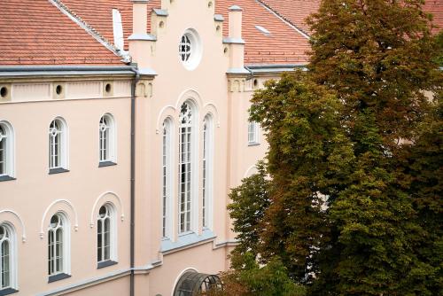 a building with white windows and a tree at Monastery Boutique Hotel Budapest in Budapest