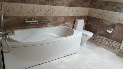 a bathroom with a white tub and a toilet at Jorela Family Hotel in Ruse