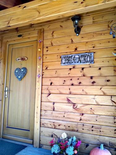 a wooden house with a door and a sign on it at Chata Nikol in Tatranská Lomnica