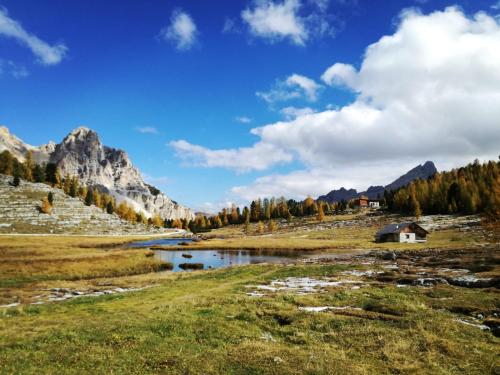 a river in a field with a house and mountains at Ciasa Raut in La Valle