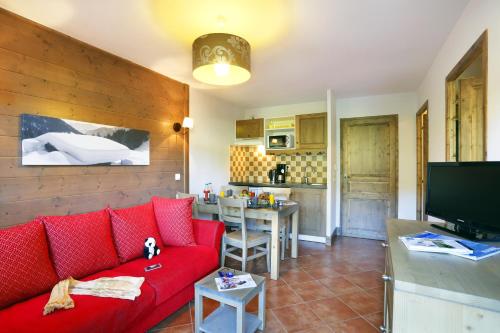 a living room with a red couch and a kitchen at Résidence Néméa Le Grand Lodge in Châtel