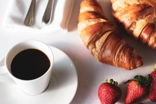 Una taza de café y un plato de croissants y fresas en Black Pearl Apartment Hotel, en Reikiavik