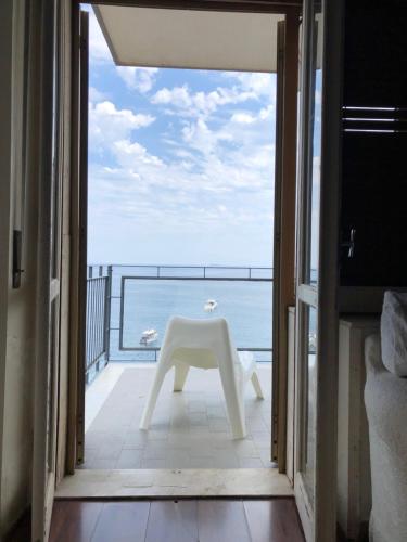 a white table on a balcony with a view of the ocean at Casa Vitale in Aci Castello