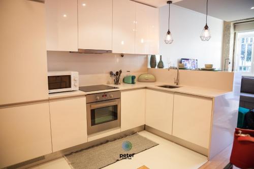 a kitchen with white cabinets and a microwave at Peter Five Flat by TonsdeVerde in Braga