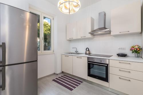 une cuisine avec des armoires blanches et un réfrigérateur en acier inoxydable dans l'établissement Kantrida Home, à Rijeka