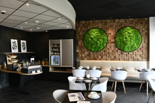 ヴァランシエンヌにあるIn Situ Hotelの白い椅子と緑の皿が壁に並ぶレストラン