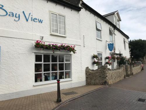 a white building with flowers in a window at Bay View Guest House in Beer