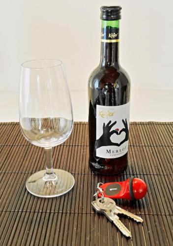 a bottle of wine and a glass and keys on a table at Design Apartment nähe Düsseldorf in Krefeld