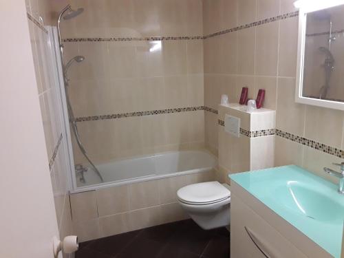 a bathroom with a tub and a toilet and a sink at Le Relais de Voisins in Voisins-le-Bretonneux