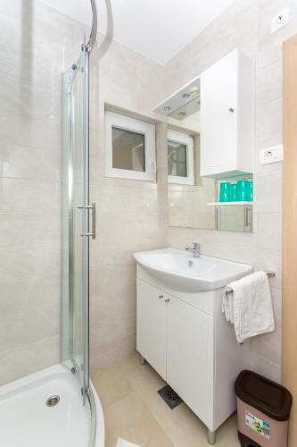 a white bathroom with a sink and a shower at Ratak House in Prizba