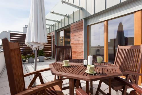 a wooden table and chairs on a balcony with an umbrella at Apartments Świnoujście Center II by Renters in Świnoujście