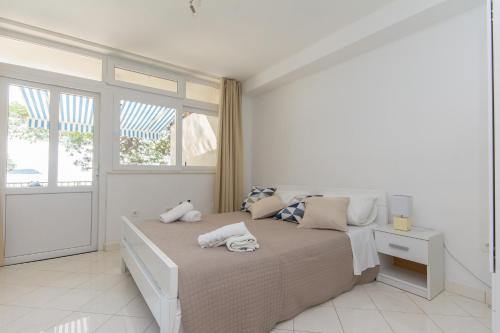 a white bedroom with a bed with towels on it at Ratak House in Prizba