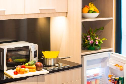 a kitchen with a microwave and some fruits and vegetables at ONOMO Hotel Conakry in Conakry