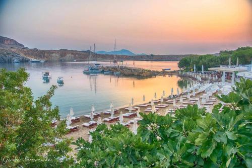 a beach with chairs and boats in the water at Lindos Vigli Private Villa in Lindos