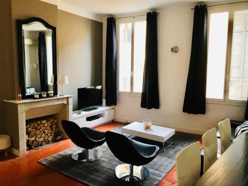 un salon avec une cheminée, des chaises et une télévision dans l'établissement Appartement coeur historique Aix, à Aix-en-Provence
