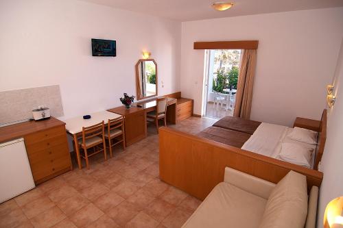 a bedroom with a bed and a kitchen and a table at Lambis Studios & Apartments in Líndos
