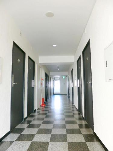 an empty hallway in an office building with a checkered floor at Hotel Chuo Oasis in Osaka