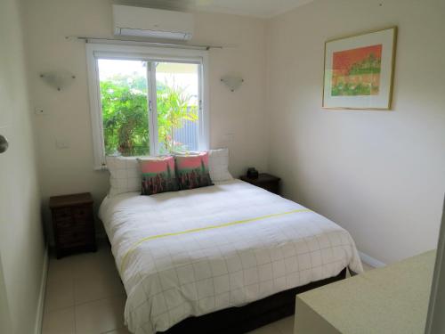 a white bed in a room with a window at Edge Hill Clean & Green Cairns, 7 Minutes from the Airport, 7 Minutes to Cairns CBD & Reef Fleet Terminal in Cairns