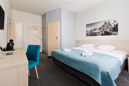 a hotel room with a bed and a blue chair at Hotel Silver in Bydgoszcz