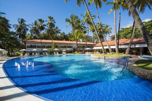 duży basen z palmami przed budynkiem w obiekcie Flat Jatiúca Suítes Resort w mieście Maceió